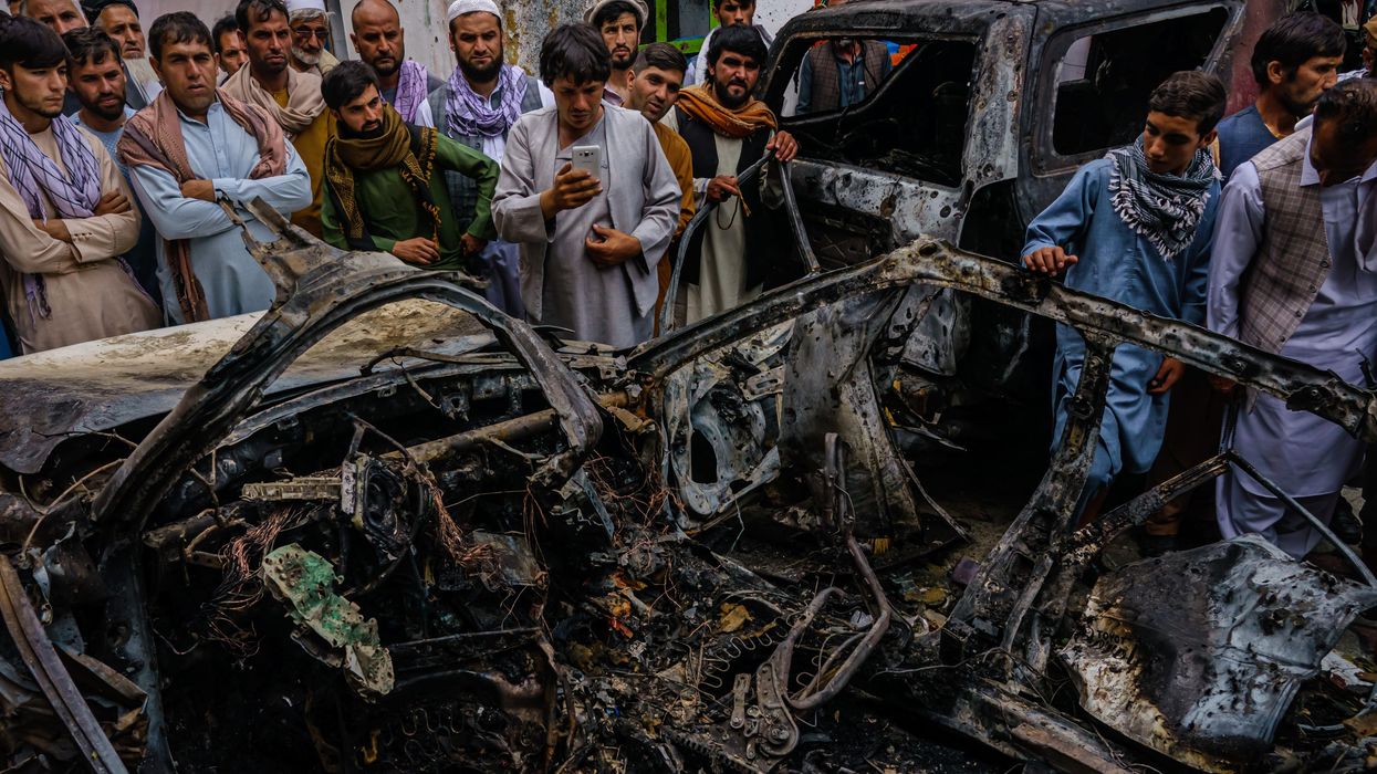 Afghans gather around a car incinerated by a U.S. drone strike
