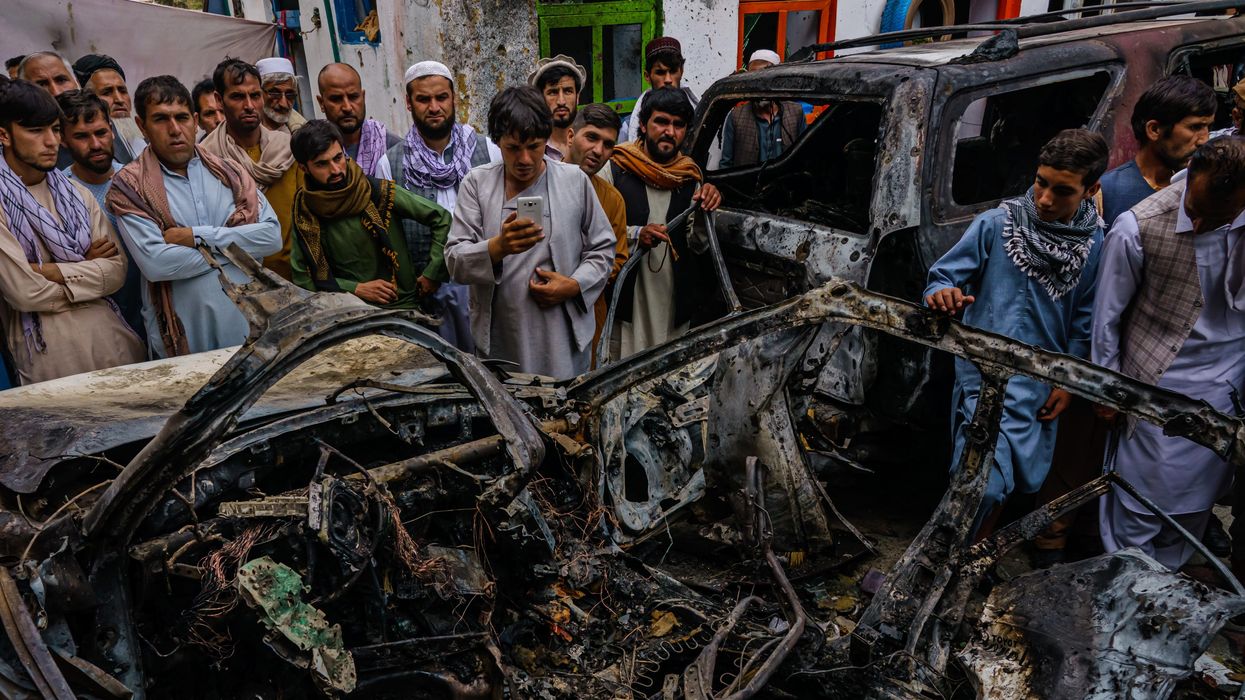 Afghans gather around a car incinerated by a U.S. drone strike