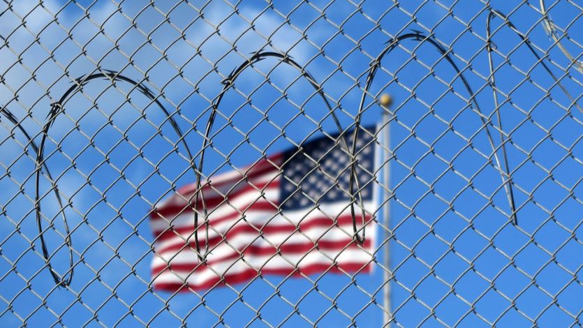 American flag behind barbed wire at offshore prison at Guantánamo Bay