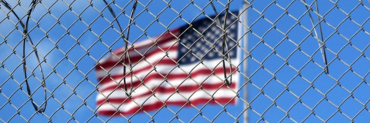 American flag behind barbed wire at offshore prison at Guantánamo Bay