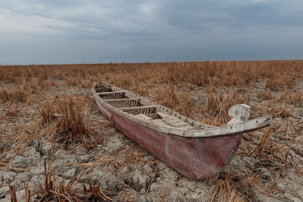 An abandoned boat in a dry marsh.