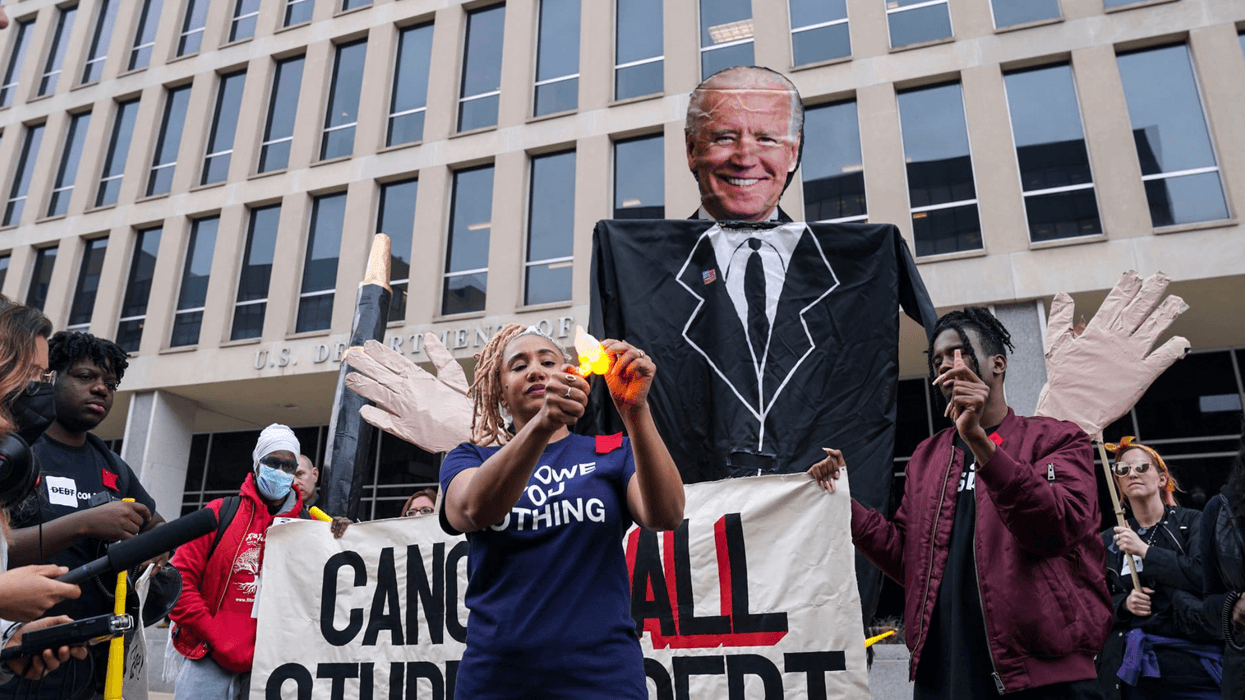 An activist burns a mock representation of her student debt balance