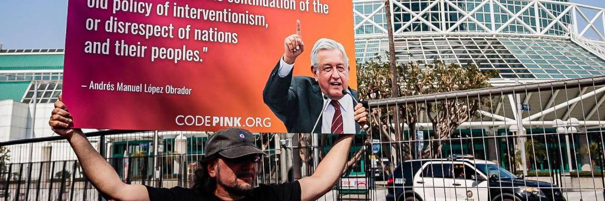 An activist carries a sign featuring Mexican President Andrés Manuel López Obrador's critique of U.S. President Joe Biden's decision to exclude Cuba, Nicaragua, and Venezuela from the Summit of the Americas in downtown Los Angeles on June 9, 2022.