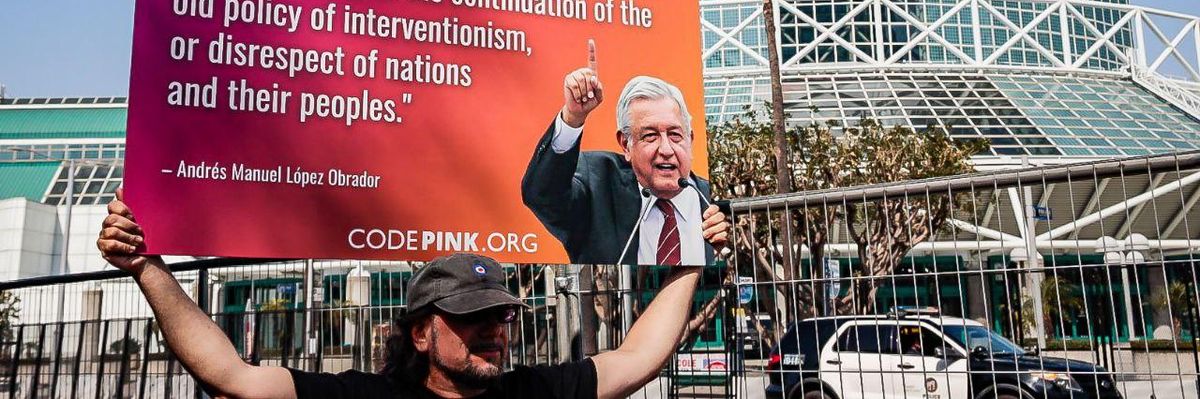 An activist carries a sign featuring Mexican President Andrés Manuel López Obrador's critique of U.S. President Joe Biden's decision to exclude Cuba, Nicaragua, and Venezuela from the Summit of the Americas in downtown Los Angeles on June 9, 2022.