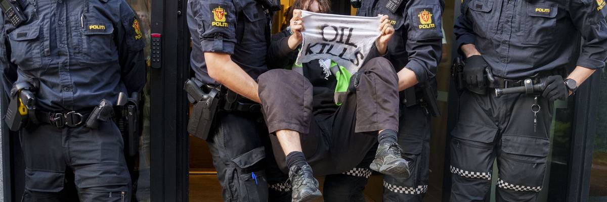An activist from the environmental movement Extinction Rebellion holds up a sign reading "Oil Kills"