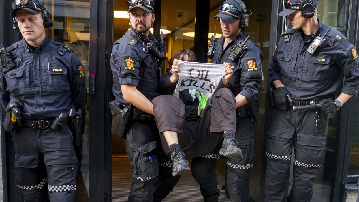 An activist from the environmental movement Extinction Rebellion holds up a sign reading "Oil Kills"