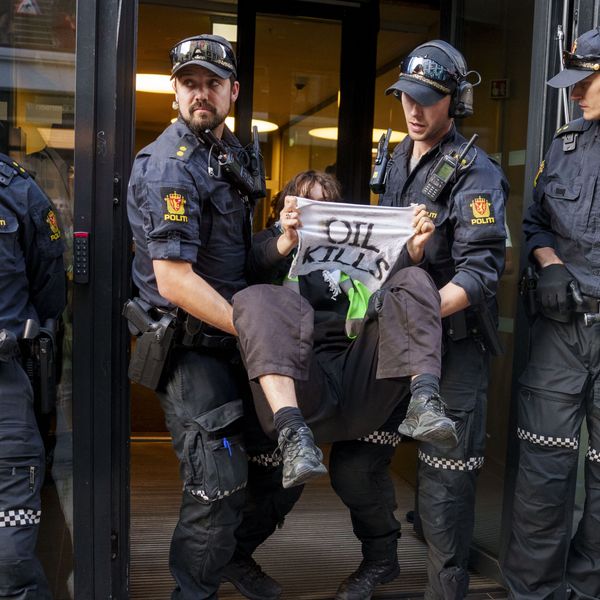 An activist from the environmental movement Extinction Rebellion holds up a sign reading "Oil Kills"
