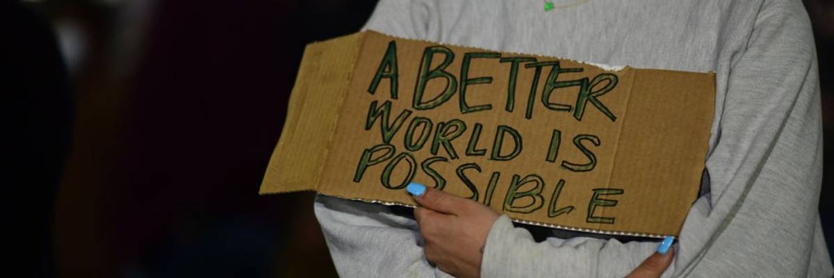 An activist holds a placard stating "A better World Is Possible