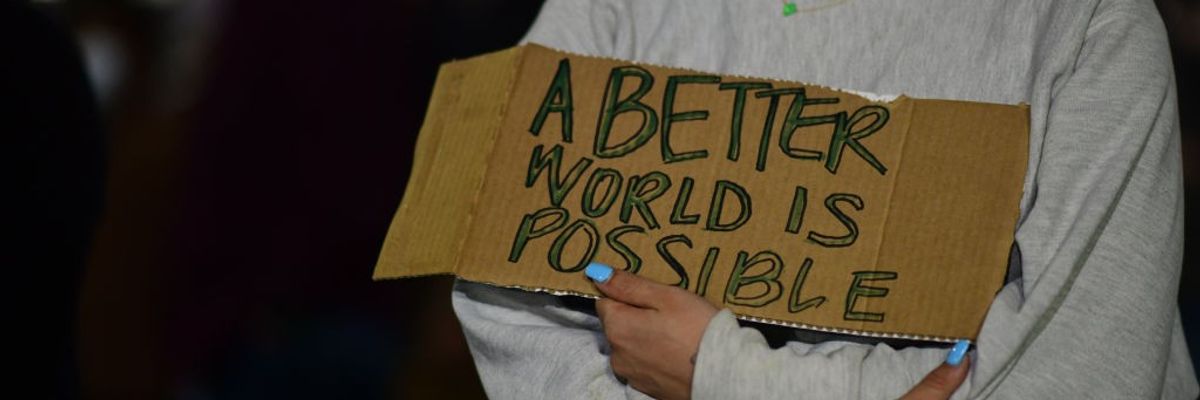 An activist holds a placard stating "A better World Is Possible