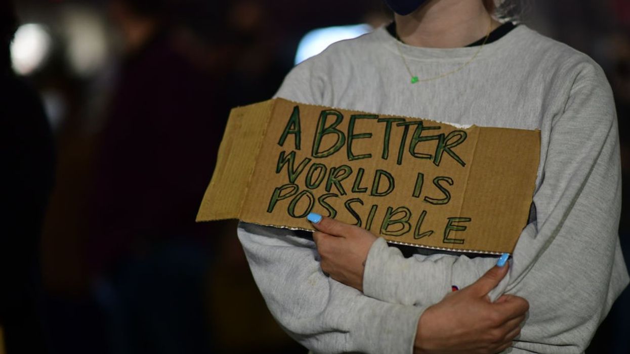 An activist holds a placard stating "A better World Is Possible