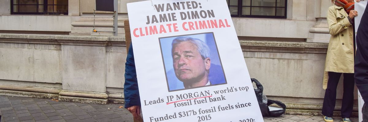 An activist holds a sign depicting JPMorgan Chase CEO Jamie Dimon and detailing information about the bank's fossil fuel financing at a protest in London on October 19, 2021.