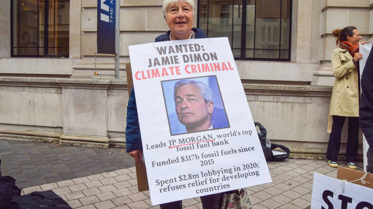 An activist holds a sign depicting JPMorgan Chase CEO Jamie Dimon and detailing information about the bank's fossil fuel financing at a protest in London on October 19, 2021.