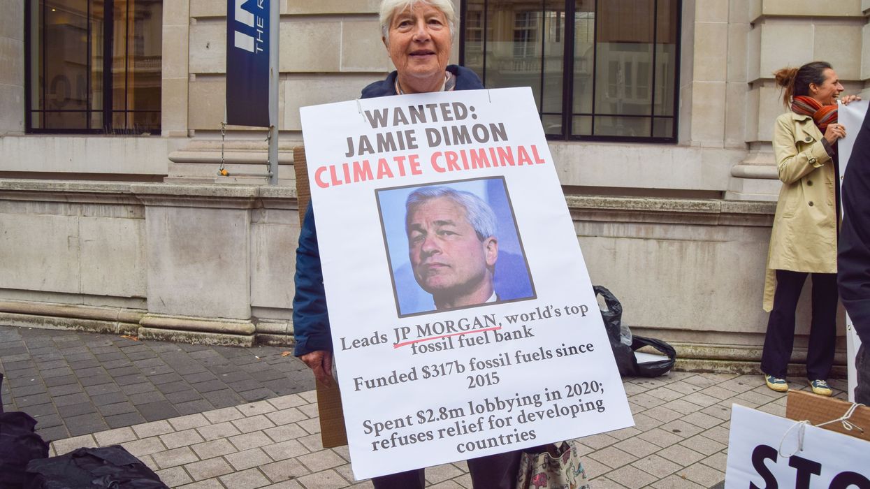An activist holds a sign depicting JPMorgan Chase CEO Jamie Dimon and detailing information about the bank's fossil fuel financing at a protest in London on October 19, 2021.