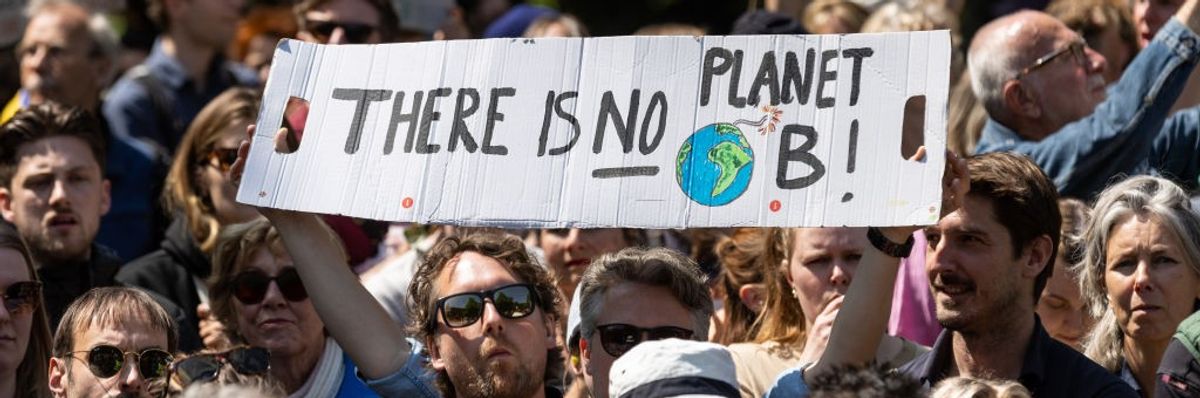 An activist in a crowd holds a white sign reading, “There is No Planet B.”