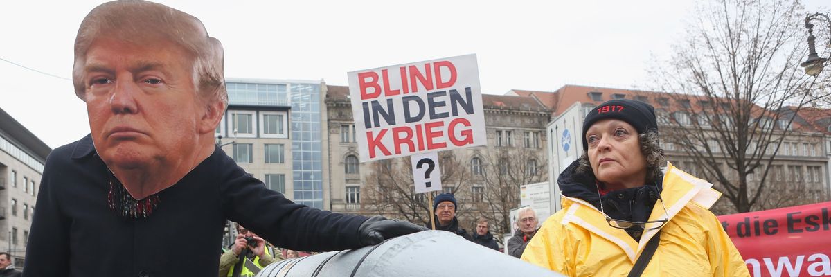 An activist in a Trump mask pats a nuclear weapon.
