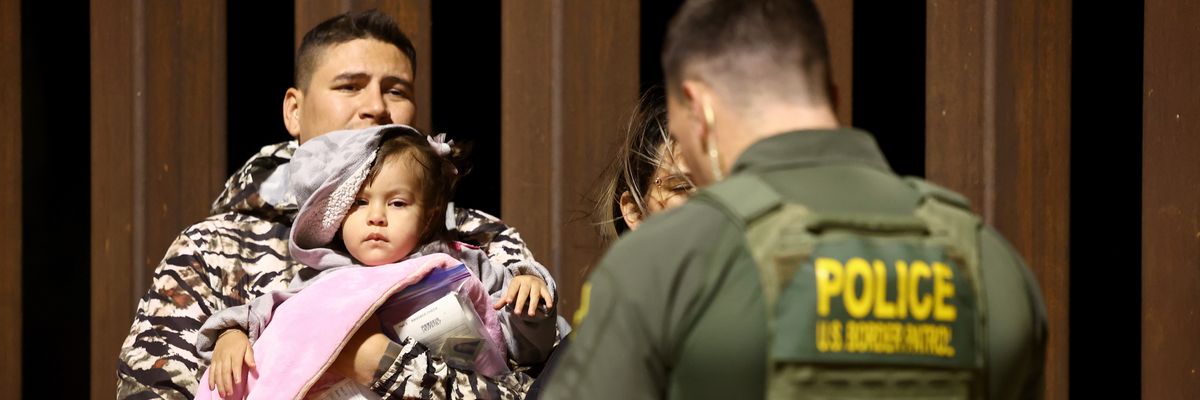 An adult and child face a U.S. Border Patrol agent. 