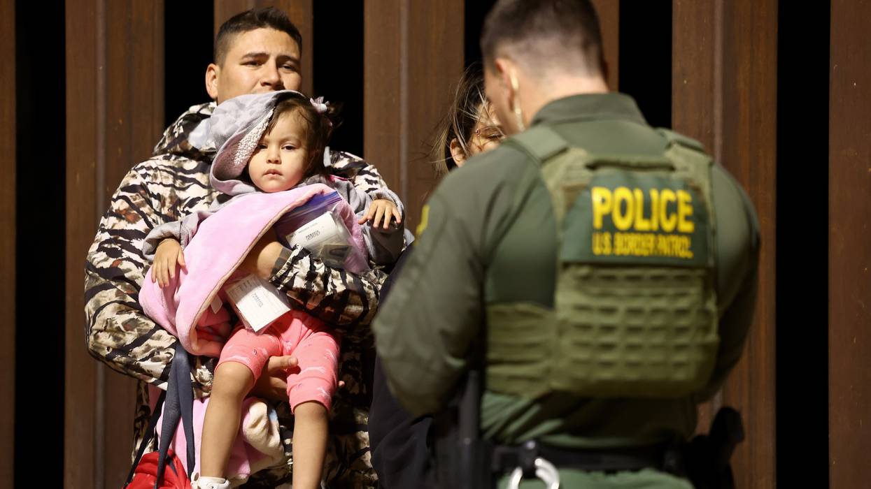 An adult and child face a U.S. Border Patrol agent.