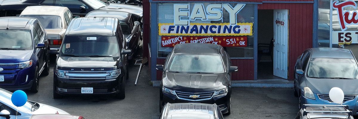 An advertisement for easy financing is posted on the front window of a used car lot