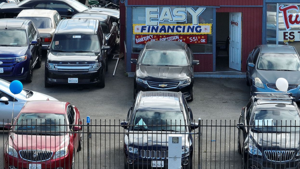 An advertisement for easy financing is posted on the front window of a used car lot