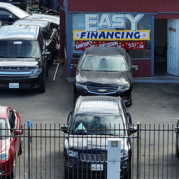 An advertisement for easy financing is posted on the front window of a used car lot