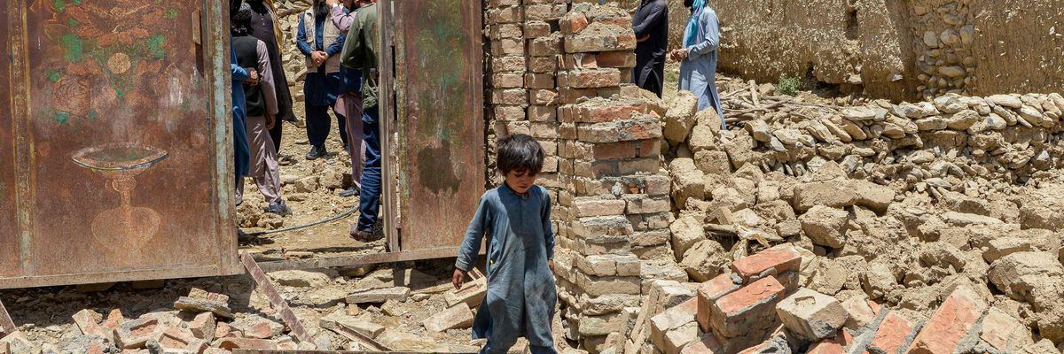 An Afghan child walks amid the rubble of his destroyed home