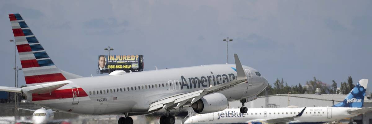 An American Airlines plane lands on a runway near a parked JetBlue plane at Florida's Fort Lauderdale-Hollywood International Airport on July 16, 2020.