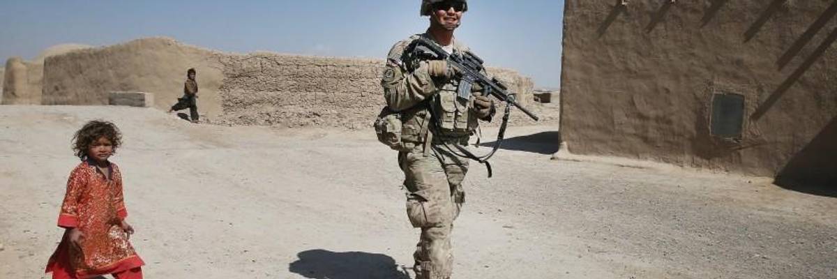 An American soldier passes an Afghan child