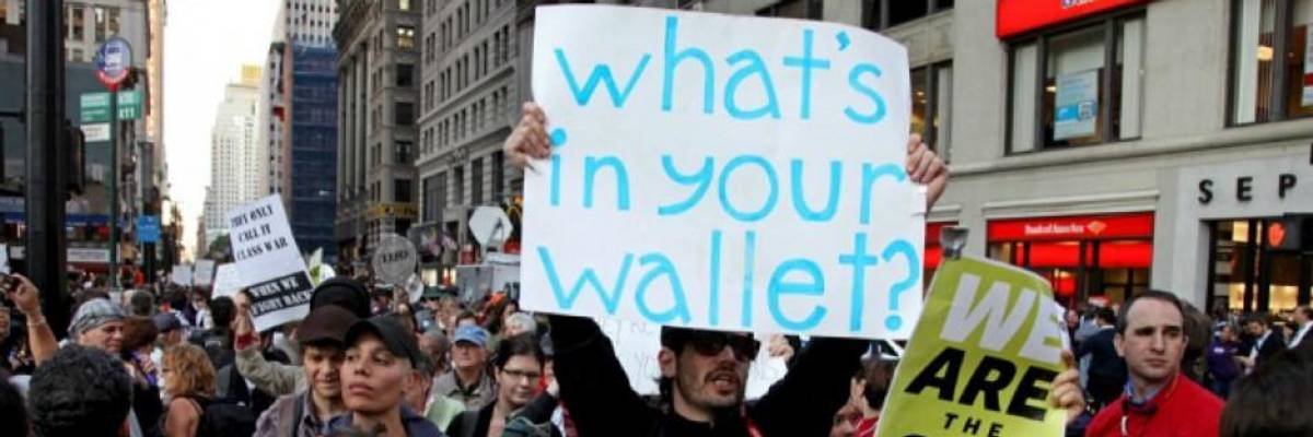 An anti-inequality protester carries a sign saying, “What’s in your wallet?”