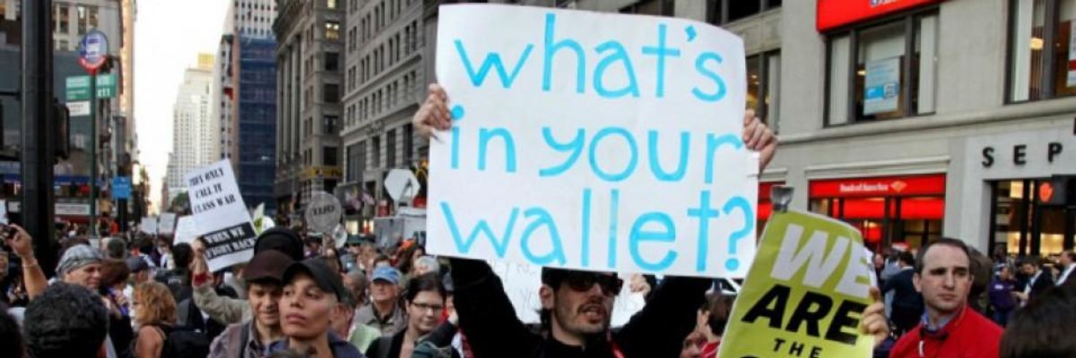 An anti-inequality protester carries a sign saying, “What’s in your wallet?”