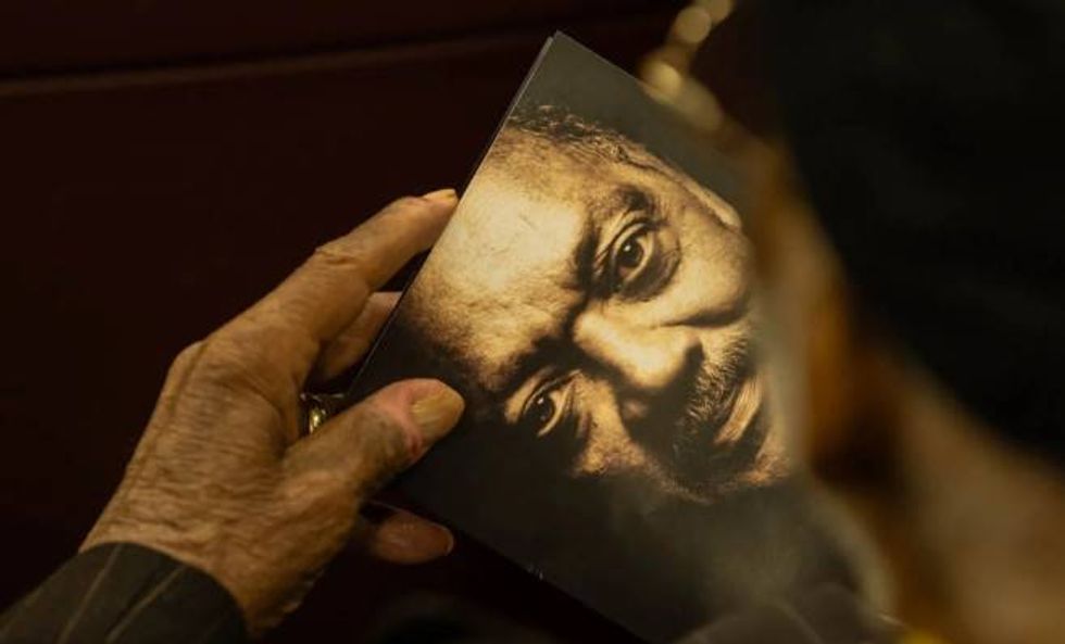 An attendee at the People's Celebration for the Rev. Jesse Jackson holds a program with his image