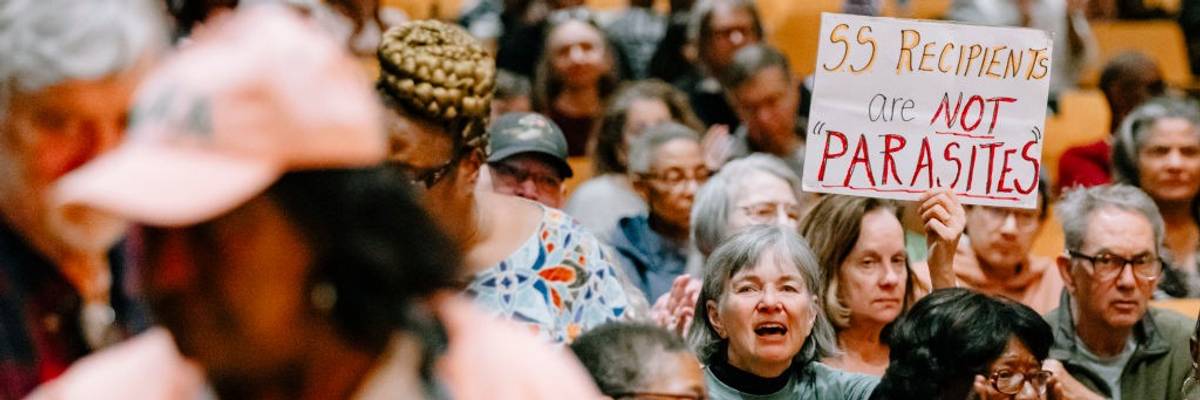 An attendee of a town hall holds up a sign in support of Social Security recipients