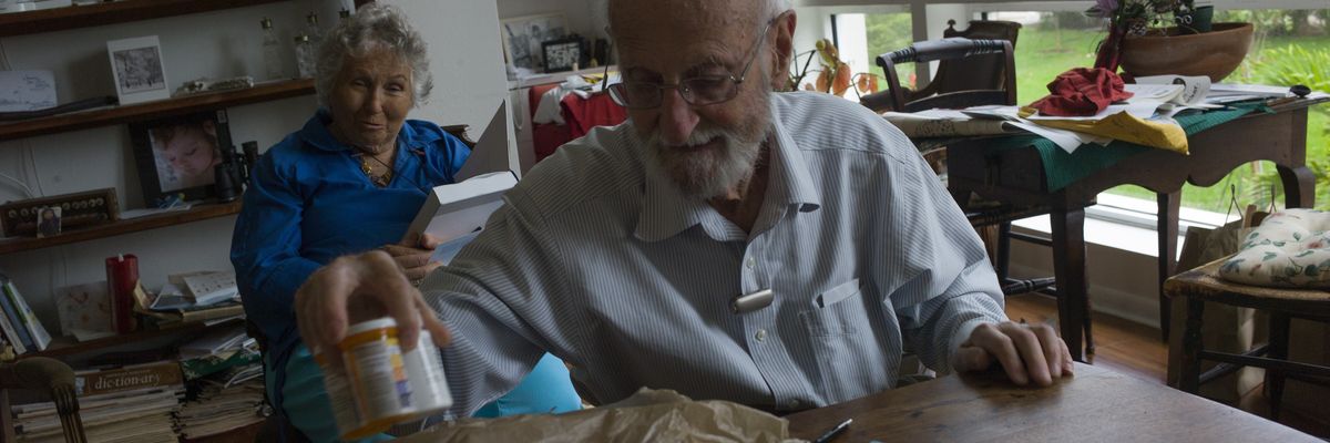 An elderly man prepares pills for his wife.