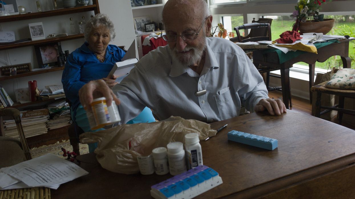 An elderly man prepares pills for his wife.