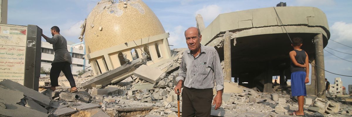 An elderly man with a cane walks near a mosque destroyed in an Israeli airstrike. 
