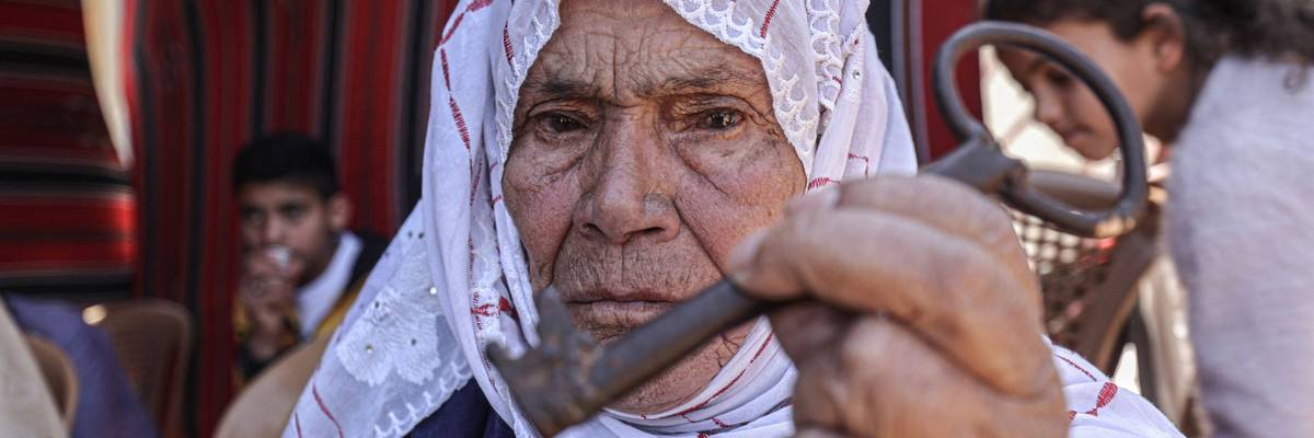 An elderly Palestinian woman holds a key symbolizing the homes they were expelled frrom during the Nakba