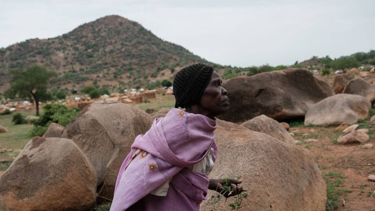 An elderly Sudanese woman gathers wild plants to use as vegetables amid famine