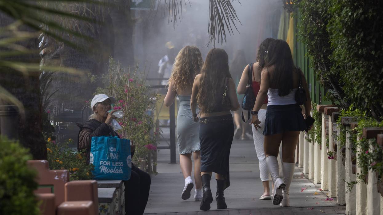 an elderly woman sits and drinks water during a heatwave.