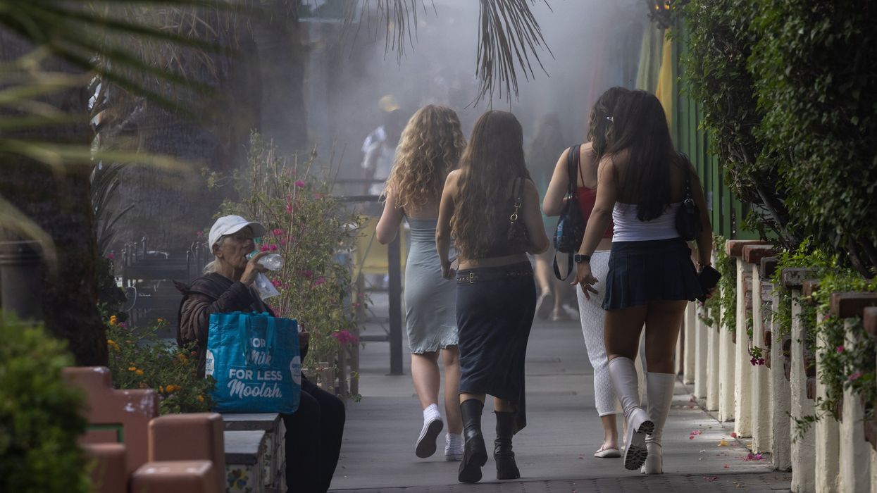 an elderly woman sits and drinks water during a heatwave.
