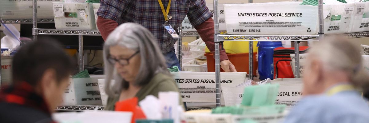 An elections worker carries a tray filled with mail-in ballots at the Maricopa County Tabulation and Election Center on November 6, 2022 in Phoenix, Arizona.