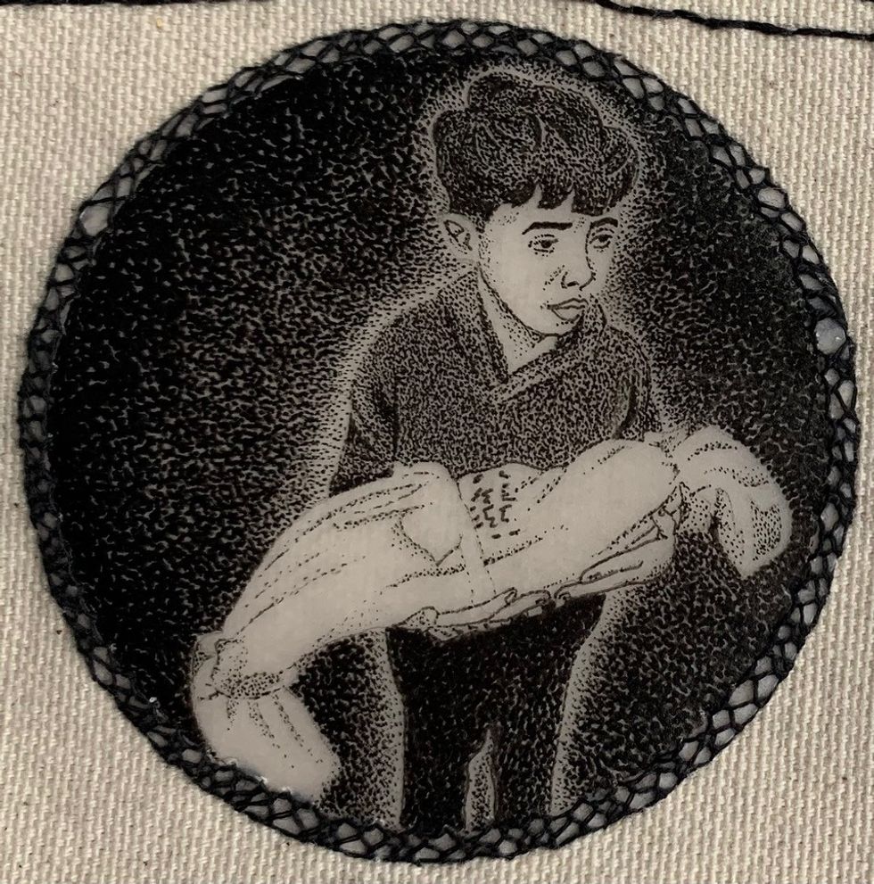 An embroidery of a Palestinian boy holding the body of his younger brother.