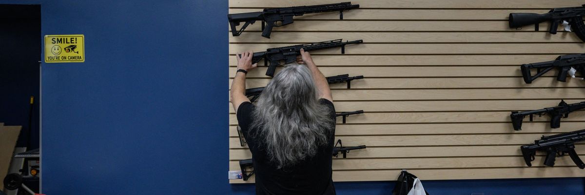 An employee arranges rifles on display