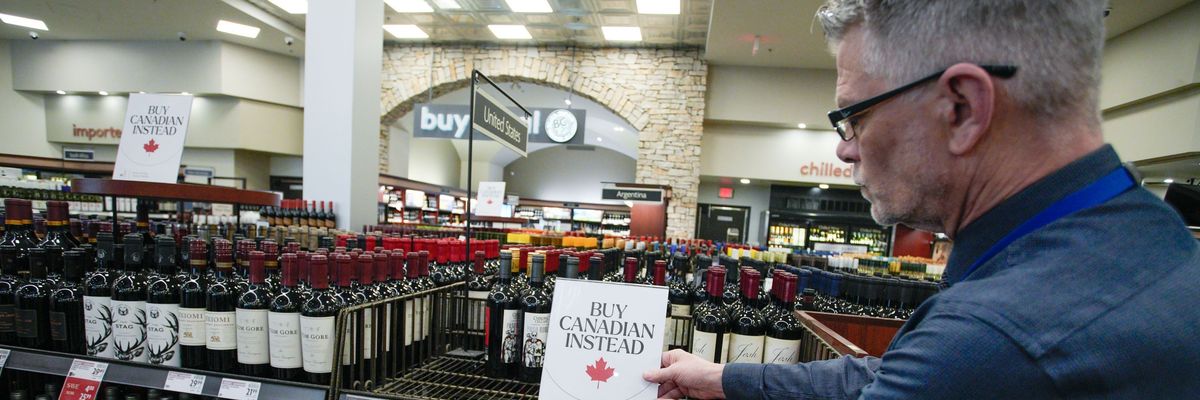 An employee places "Buy Canadian Instead" signs on a shelf at a liquor store