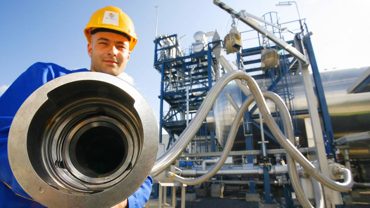An employee poses with a pipe used to carry liquid CO2