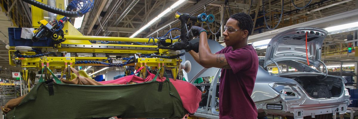 An employee uses a robotic arm to help lift internal parts