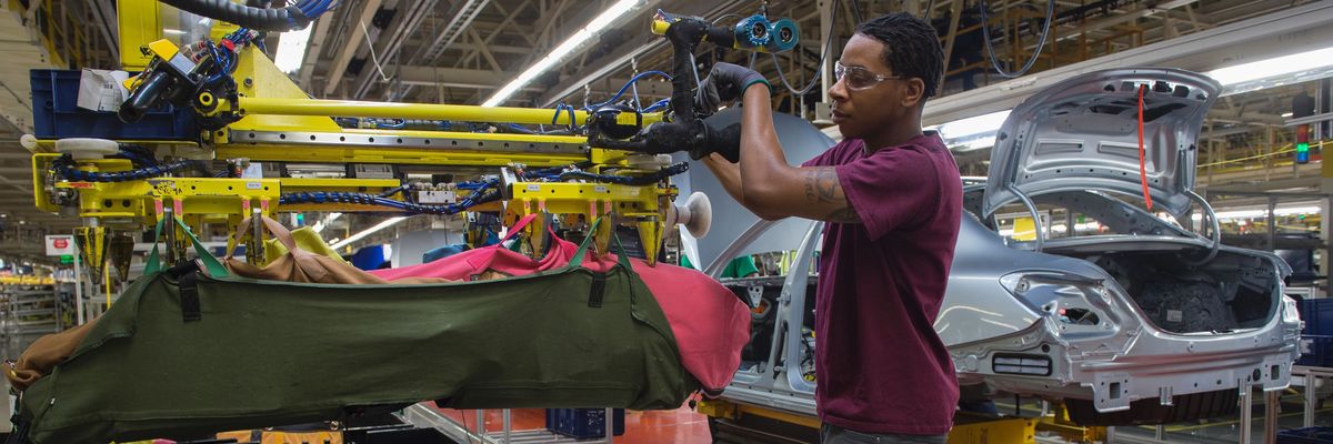 An employee uses a robotic arm to help lift internal parts