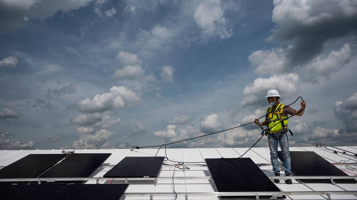 An employee with Ipsun Solar installs solar panels on the roof of the Peace Lutheran Church in Alexandria, Virginia on May 17, 2021.
