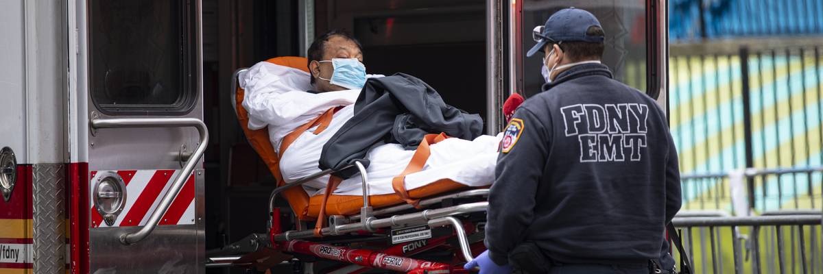 An FDNY EMT helps patient a with Covid-19 out of an ambulance.