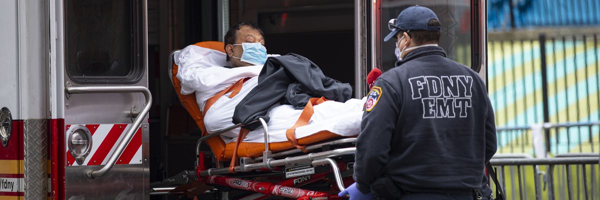 An FDNY EMT helps patient a with Covid-19 out of an ambulance.