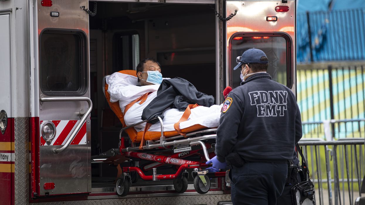 An FDNY EMT helps patient a with Covid-19 out of an ambulance.