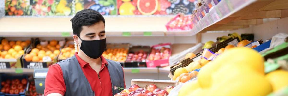 An grocery store employee wearing a face mask fills up a shelf of vegetables on April 22, 2020 in Rosenheim, Bavaria